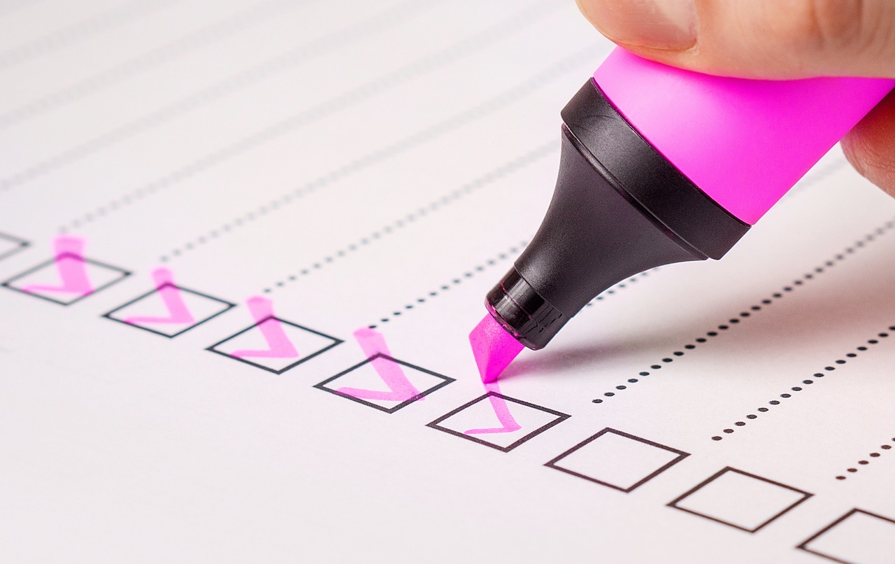 Ein Blatt Papier mit einer Checkliste und ein rosa Textmarker welcher die einzelnen Punkte abhakt.